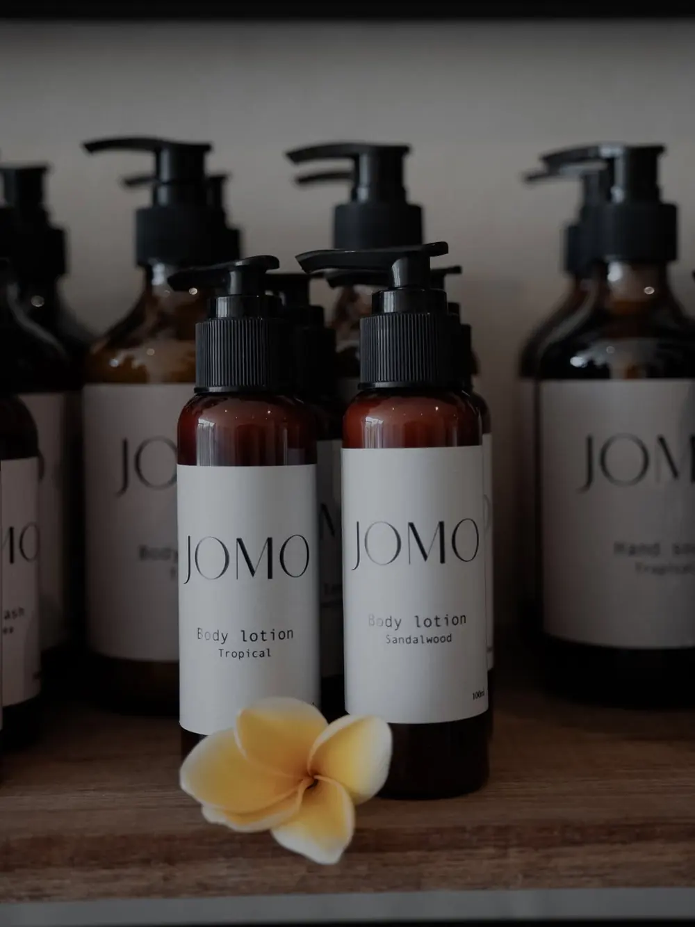 JOMO body care bottles with a frangipani